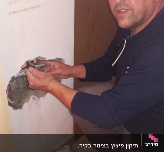 אדם עובד על קיר עם כלי עבודה